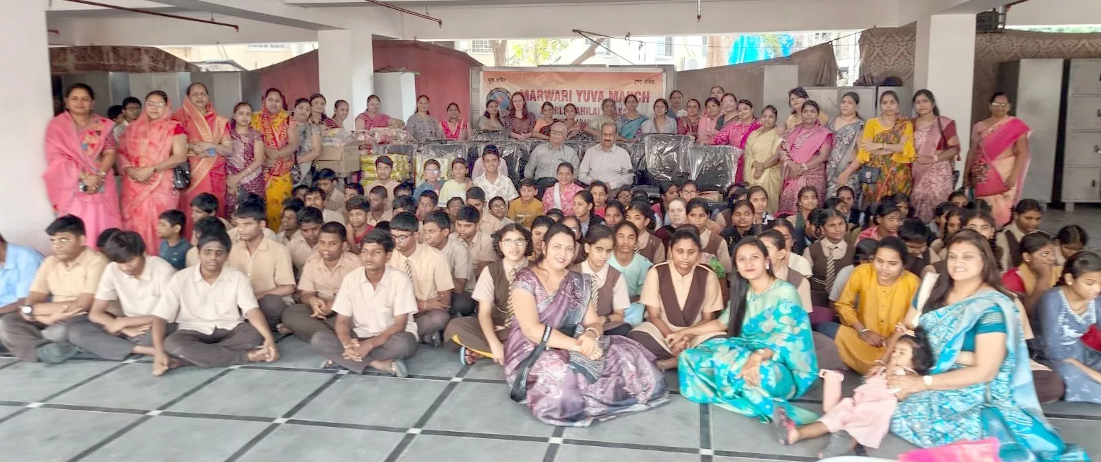 सेवा कार्यक्रम में बच्चों को सामग्री प्रदान करते सदस्य