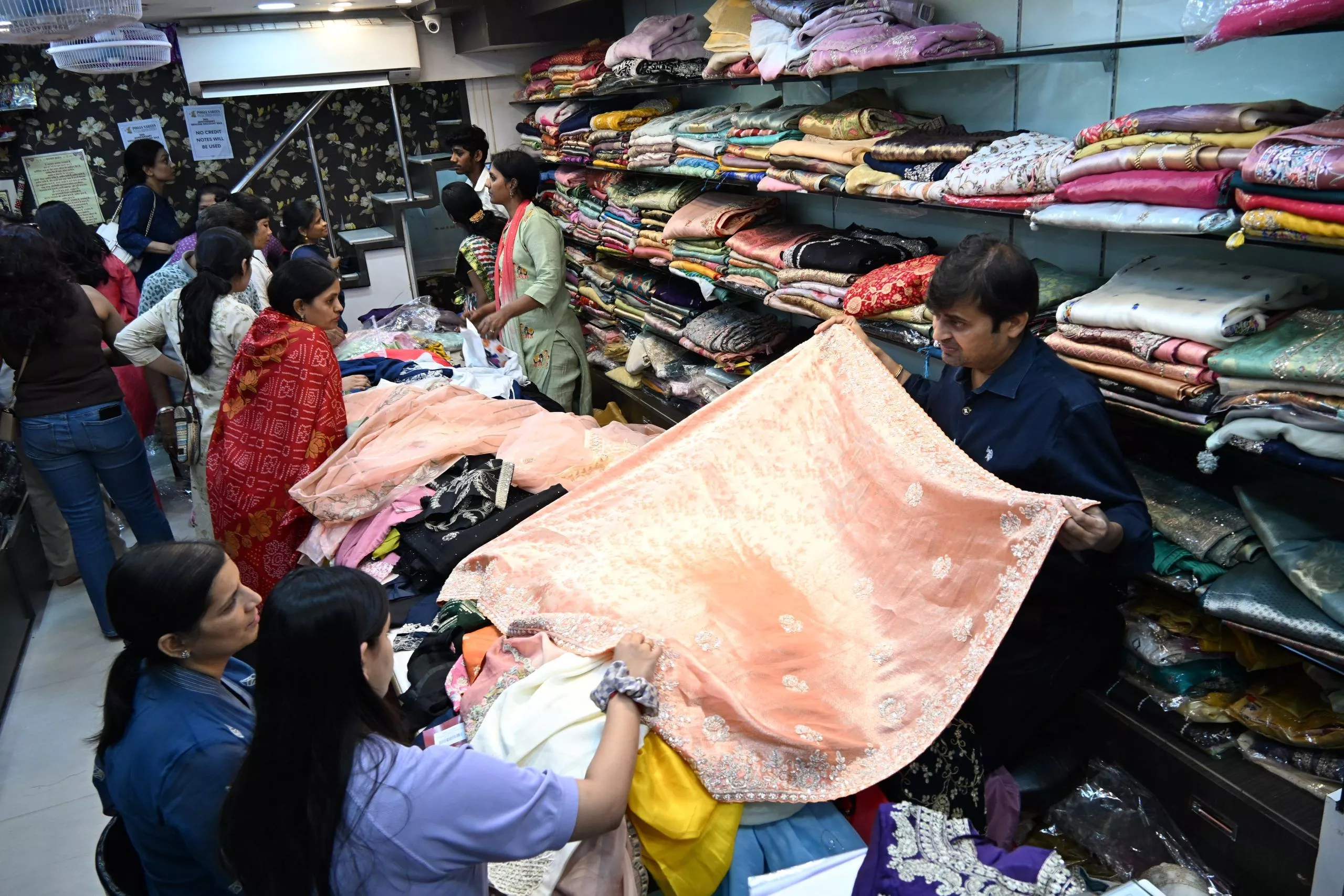 पूजा साड़ी स्टोर में साड़ियों की सेल का दृश्य