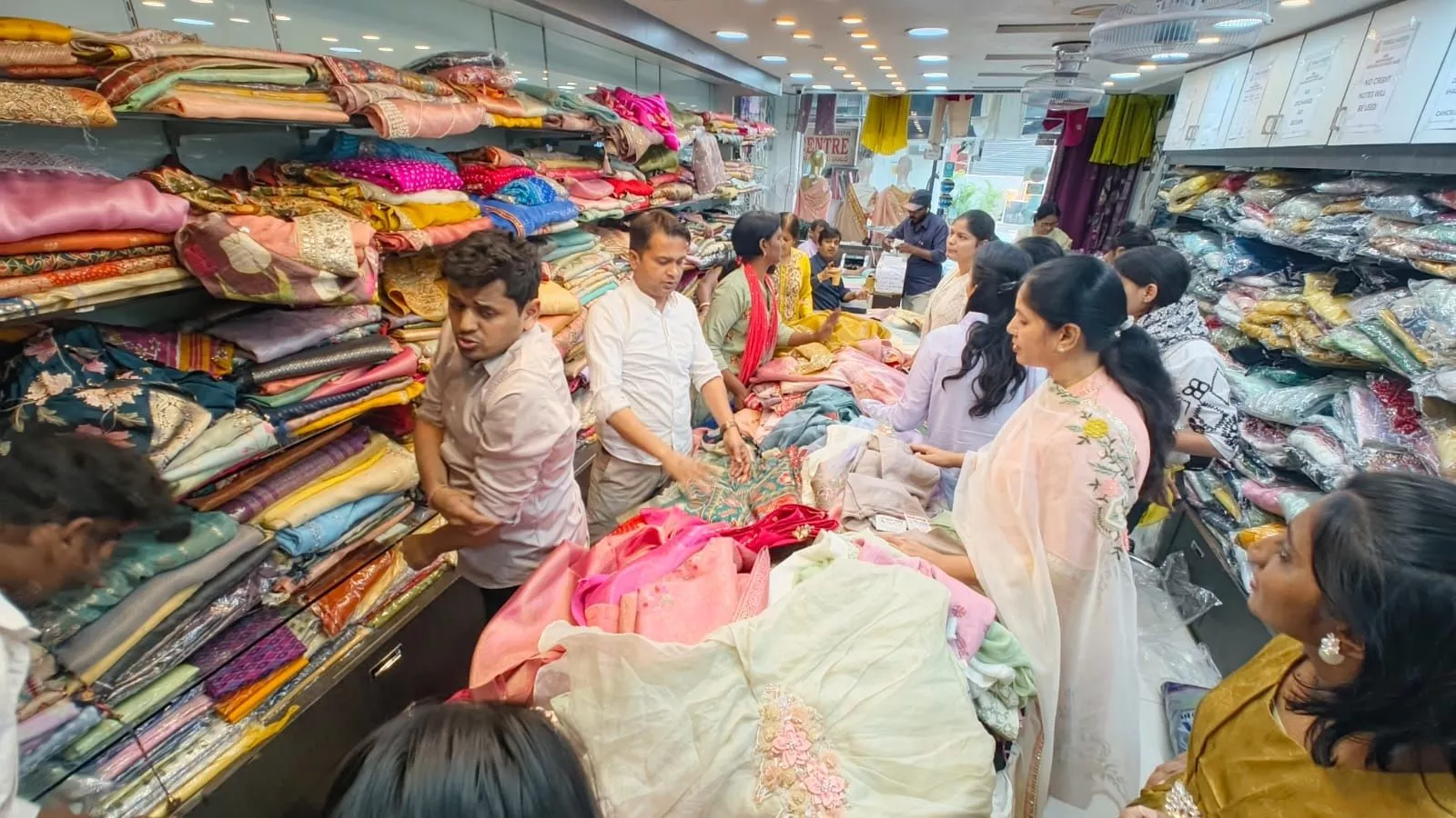पूजा साड़ी स्टोर में साड़ियों की सेल का दृश्य