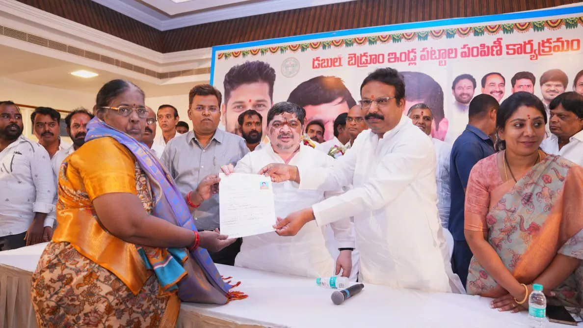 मंत्री पोन्नम लाभार्थियों को डबल बेडरूम आवास पट्टे देते हुए