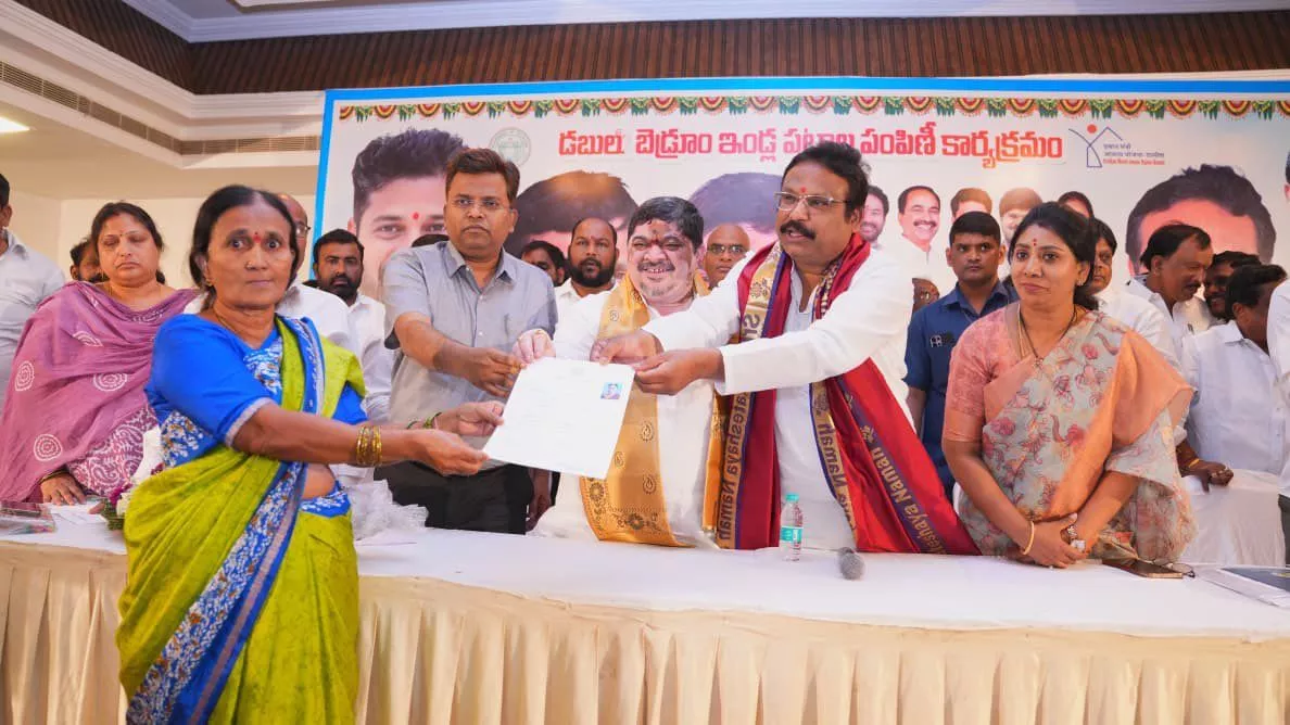 मंत्री पोन्नम लाभार्थियों को डबल बेडरूम आवास पट्टे देते हुए