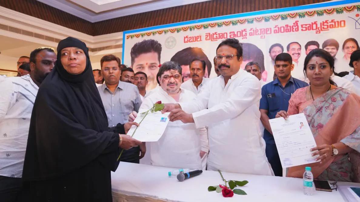 मंत्री पोन्नम लाभार्थियों को डबल बेडरूम आवास पट्टे देते हुए