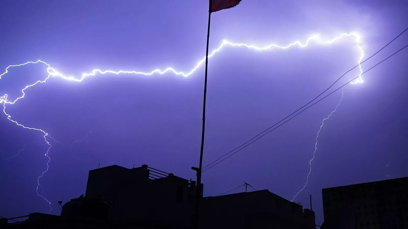 आंधी-तूफान में खेत के पास गिरती आकाशीय बिजली